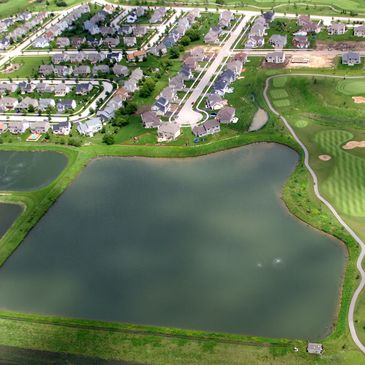 Aerial view of a residential area next to a large pond and golf course.