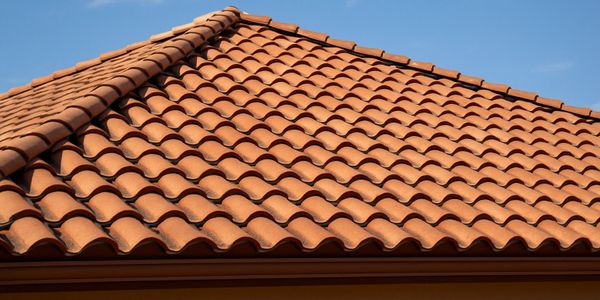 Close-up of a terracotta tiled roof under a clear blue sky.