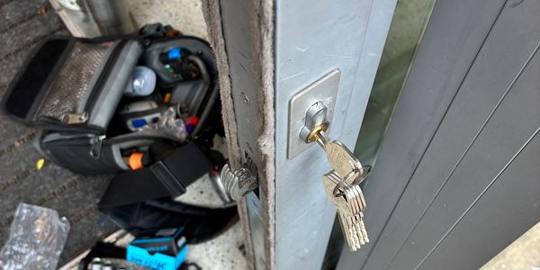 Keys inserted in a door lock with a technician's toolkit nearby.