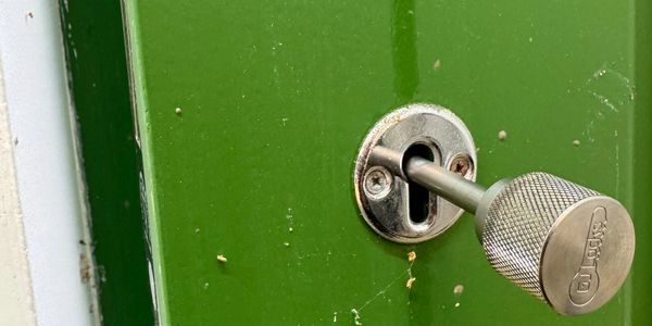 A silver key inserted into a green door lock.