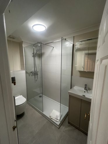 Modern bathroom with glass shower and gray tones.
