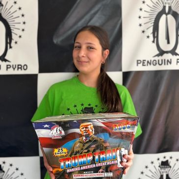 A girl holding a Trump Train fireworks box, smiling.