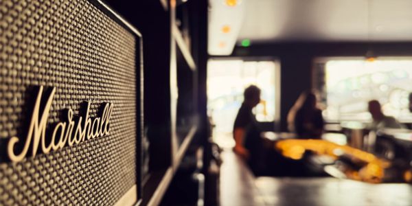 Close-up of a Marshall amplifier in a cozy, dimly lit room with people in the background.