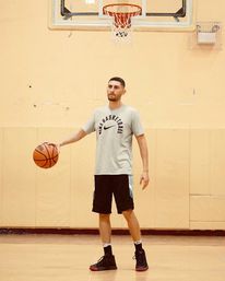Man standing on a basketball court holding a basketball.