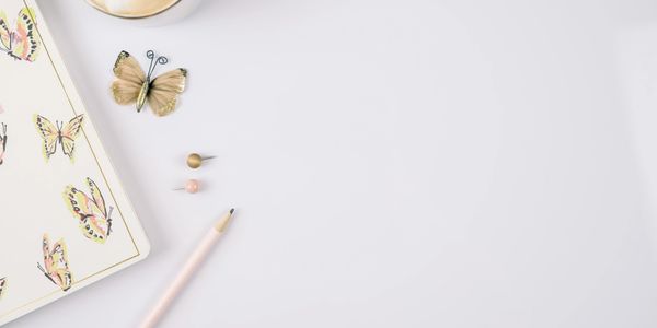 Butterfly-themed stationery with a pencil and decorative pins on a white surface.