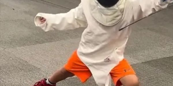 Child practicing fencing outdoors.