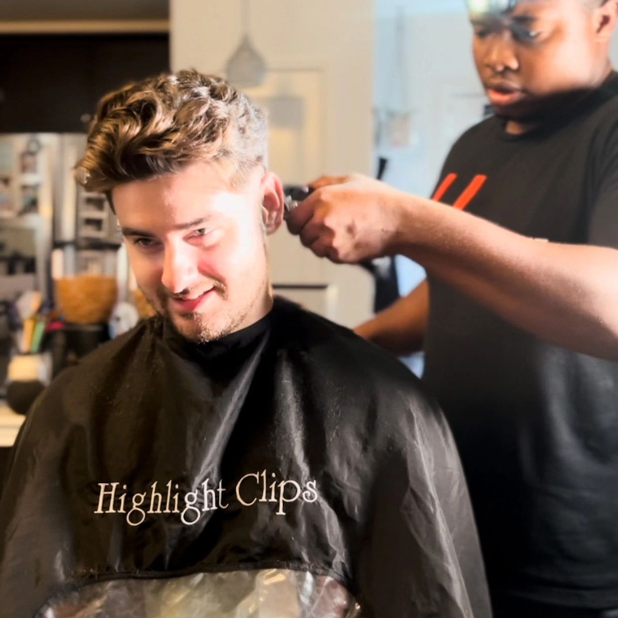 Photo of Mobile Barber cutting a client hair in a black highlight clips barber cape 