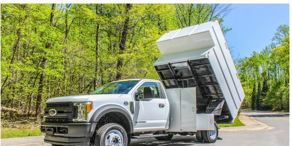 White dump truck with raised bed on a road.