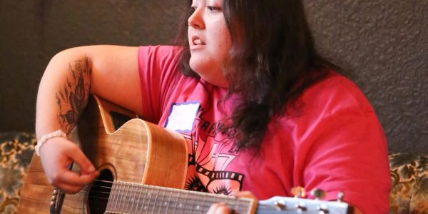 Person playing an acoustic guitar indoors.