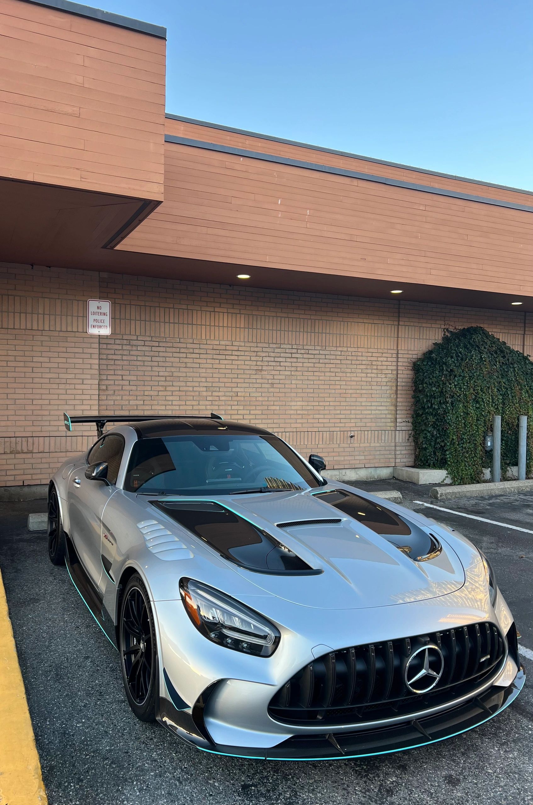 Silver Mercedes-AMG GT sports car parked beside a brick wall.