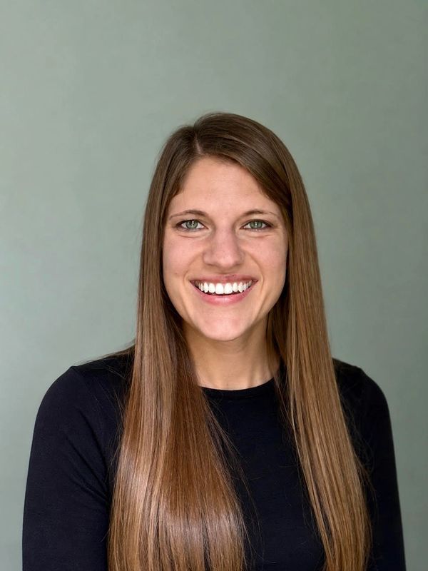 Smiling woman with long brown hair and green eyes.