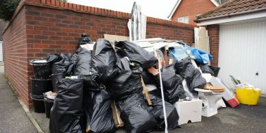 Pile of black garbage bags outside a house.