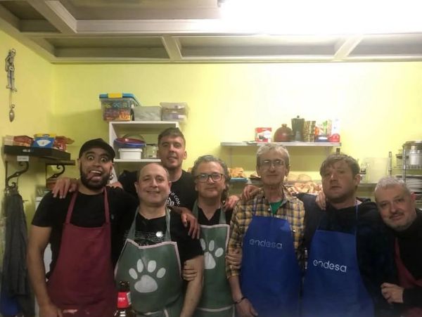 Grupo de siete hombres con delantales en una cocina.