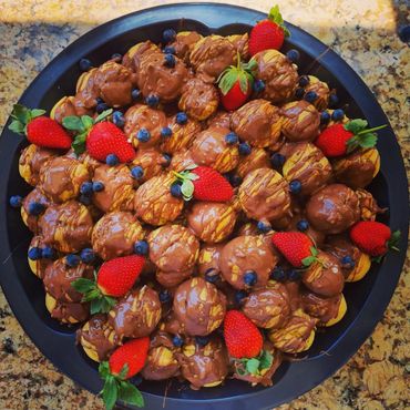Plate of chocolate-covered treats with strawberries and blueberries.