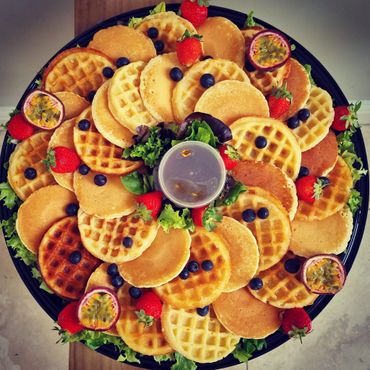 A colorful platter of mini pancakes and waffles with fresh berries and passion fruit.