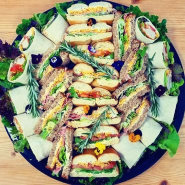 A platter of assorted sandwiches and wraps garnished with herbs and edible flowers.