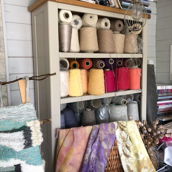 Shelf with colorful yarn spools and fabrics.