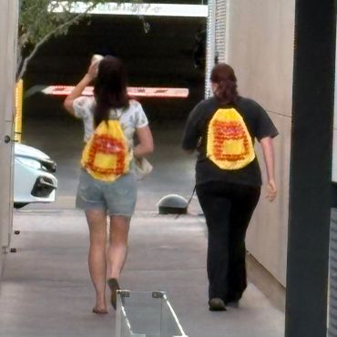 Two women walking with colorful backpacks.