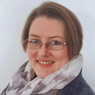 Smiling woman wearing glasses and a scarf.