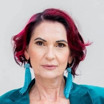 Portrait of a woman with red hair and blue tassel earrings.