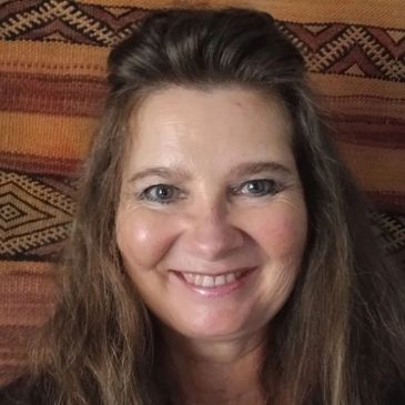 Smiling woman with long hair against a textured patterned background.