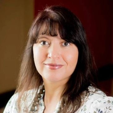 Portrait of a smiling woman with dark hair and bangs.