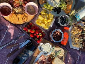 A cozy picnic spread with fruits, cheese, crackers, and wine.