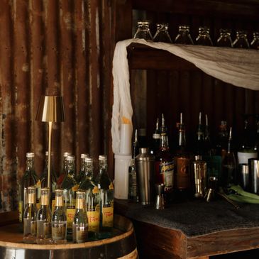 Rustic bar setup with bottles and gold lamp.