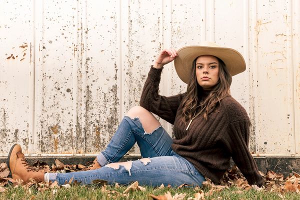 Portrait of woman in hat sitting on ground.