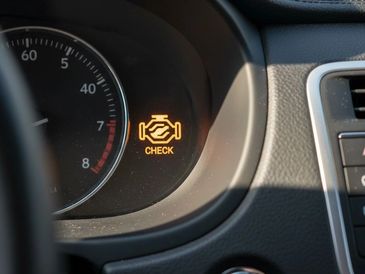 Car dashboard displaying a check engine warning light.