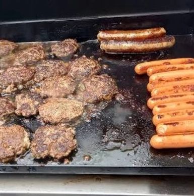 Grilled burgers and hot dogs on a flat top grill.