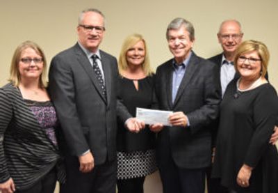 Group of six people posing with a check.