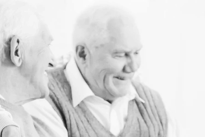Two elderly men smiling and enjoying a conversation.