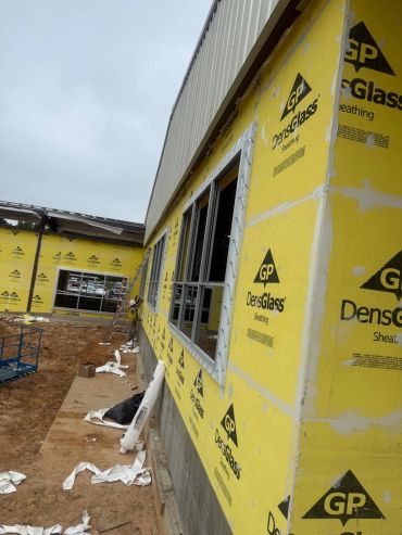 Construction site with yellow DensGlass sheathing on walls.