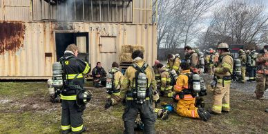 Firefighters gathered outside a training structure.