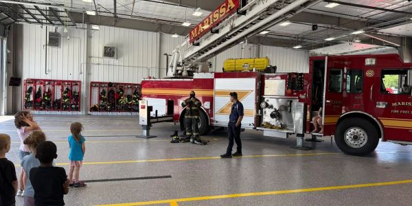 Firefighter demonstration for children inside fire station.