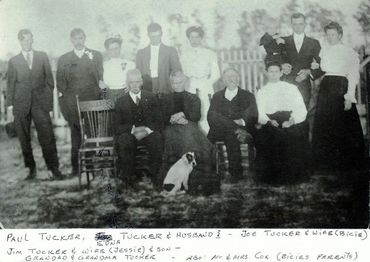 A vintage black-and-white family portrait with multiple generations and a dog.
