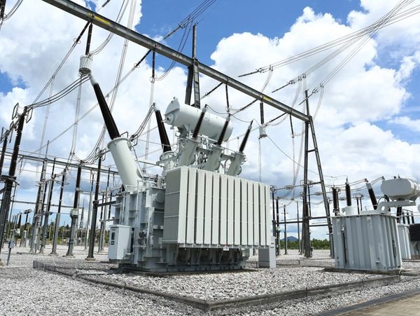 Large electrical transformer in a power substation under a partly cloudy sky.