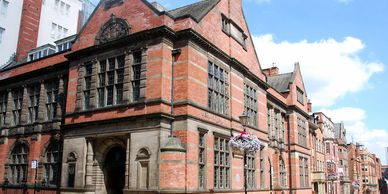 Historic red brick building with large windows under a blue sky.