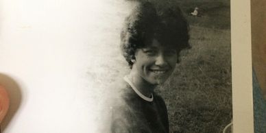 Black and white photo of a smiling woman outdoors.