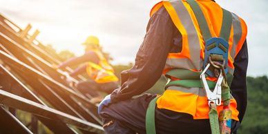 Construction workers wearing safety harnesses and reflective vests.