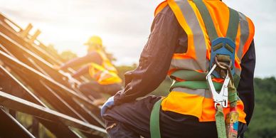 Construction workers wearing safety harnesses and reflective vests.