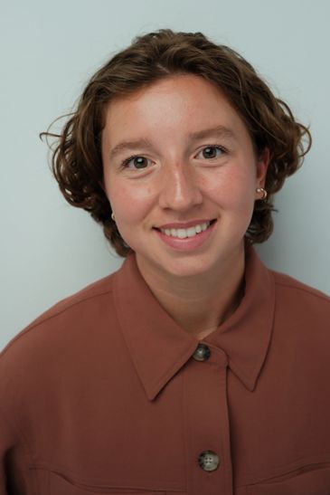 Young woman smiling with short curly hair.