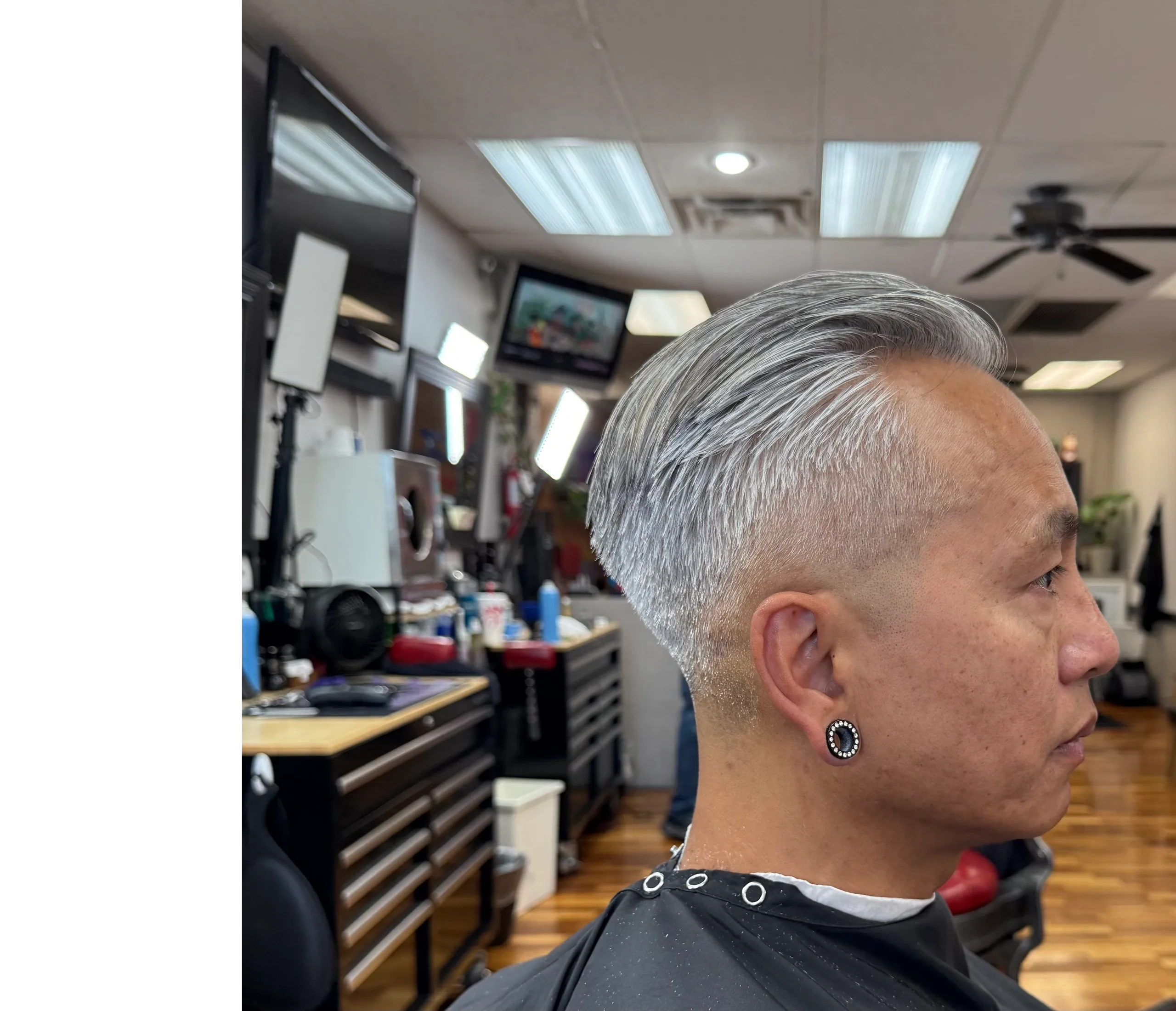 Side profile of a man with a sleek silver pompadour haircut Crispcutz barbershop.
