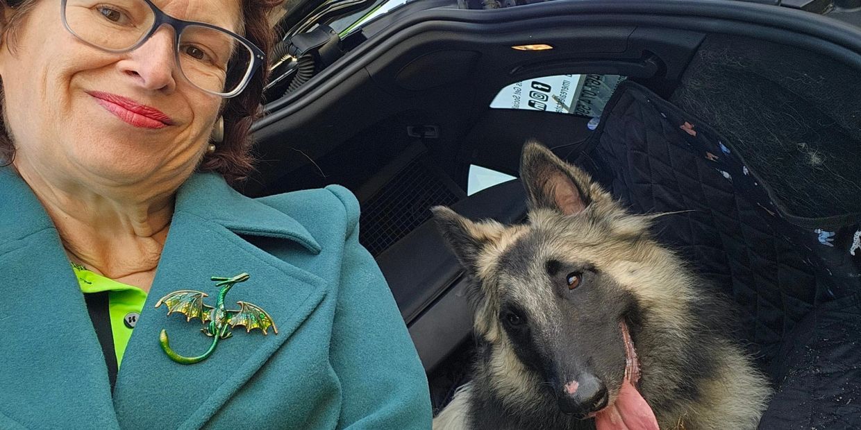 Woman smiling with a dog in the car.