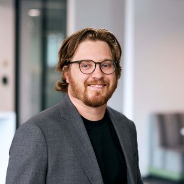 Man with glasses smiling in an office.