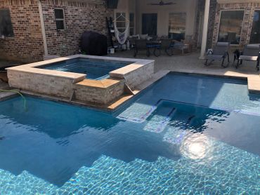 Modern backyard pool with spa and seating area.