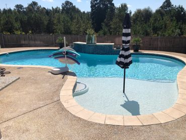 Swimming pool with a black and white striped umbrella.