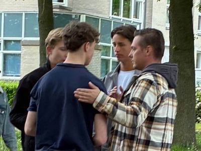 Four young men engaged in a serious outdoor conversation.