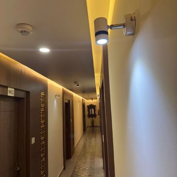 A well-lit hotel corridor with wooden doors and decorative tile flooring.
